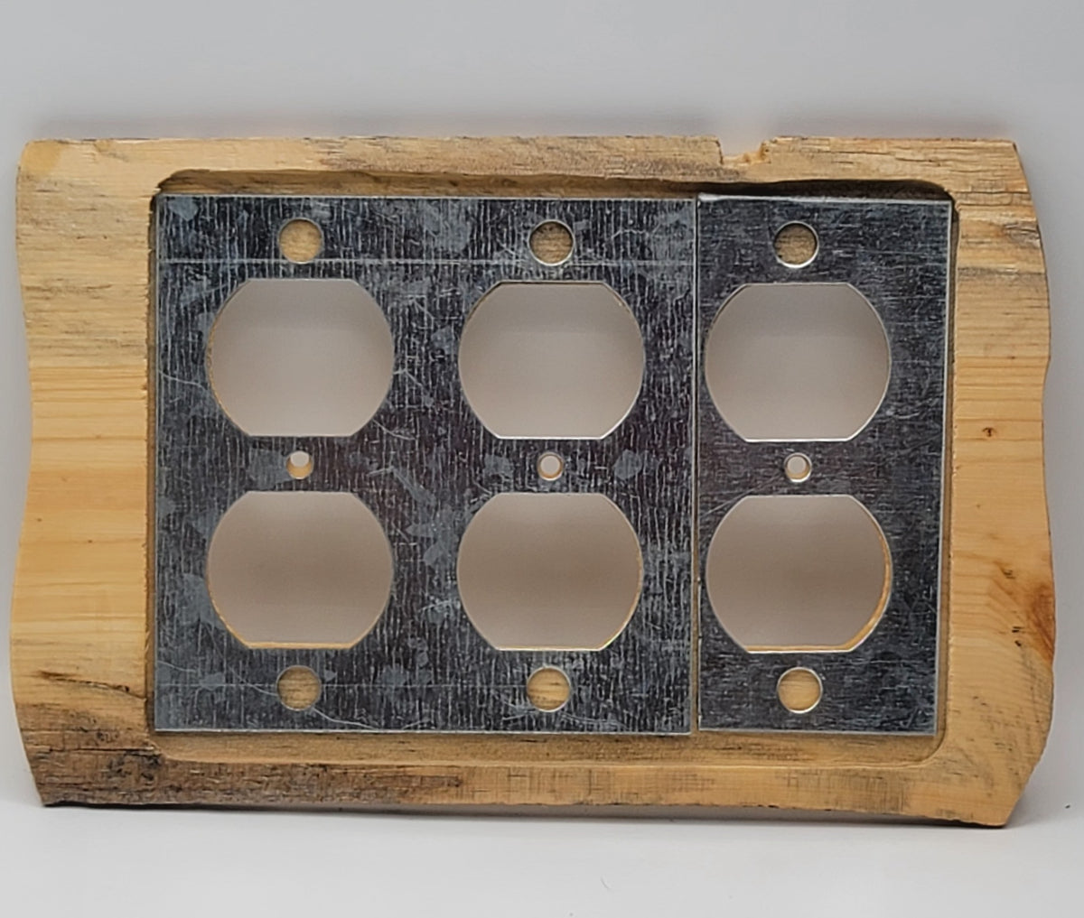 A rustic electrical outlet cover plate featuring a natural wood frame and a dark, weathered metal insert with six cutouts.