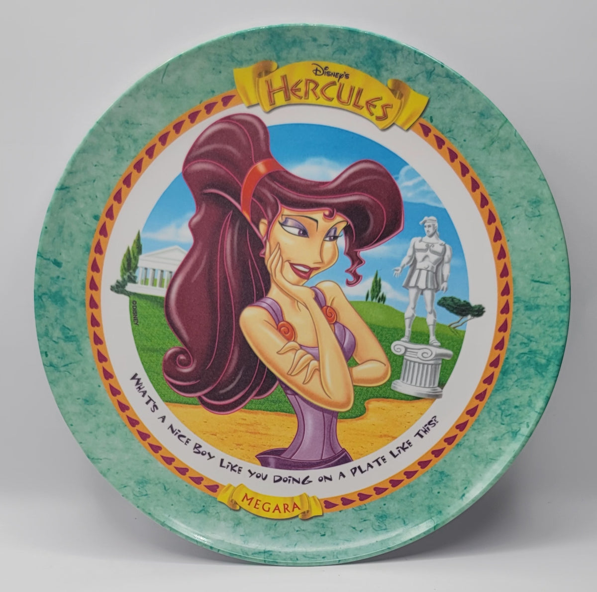 A round decorative plate featuring Disney's Hercules artwork, with a central illustration of Megara and the title 'Hercules' at the top, photographed against a neutral gray background.