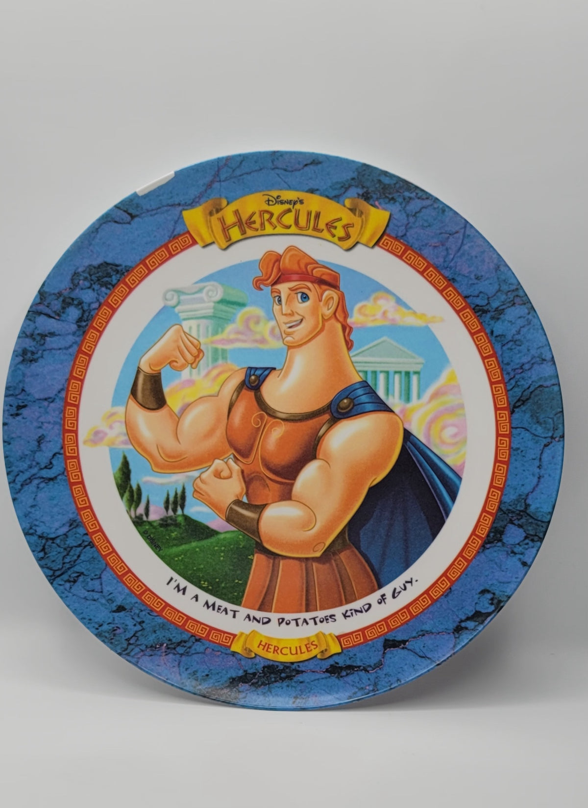 Disney Hercules collectible ceramic plate featuring the character flexing his muscles, set against a blue marbled background with a white center and yellow title banner.