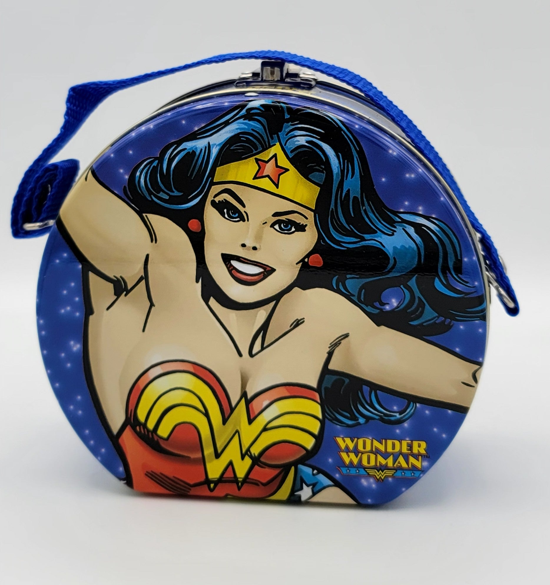 A round metal clutch purse featuring a colorful Wonder Woman comic illustration on a blue starry background, with a blue shoulder strap and silver-tone metal clasp.