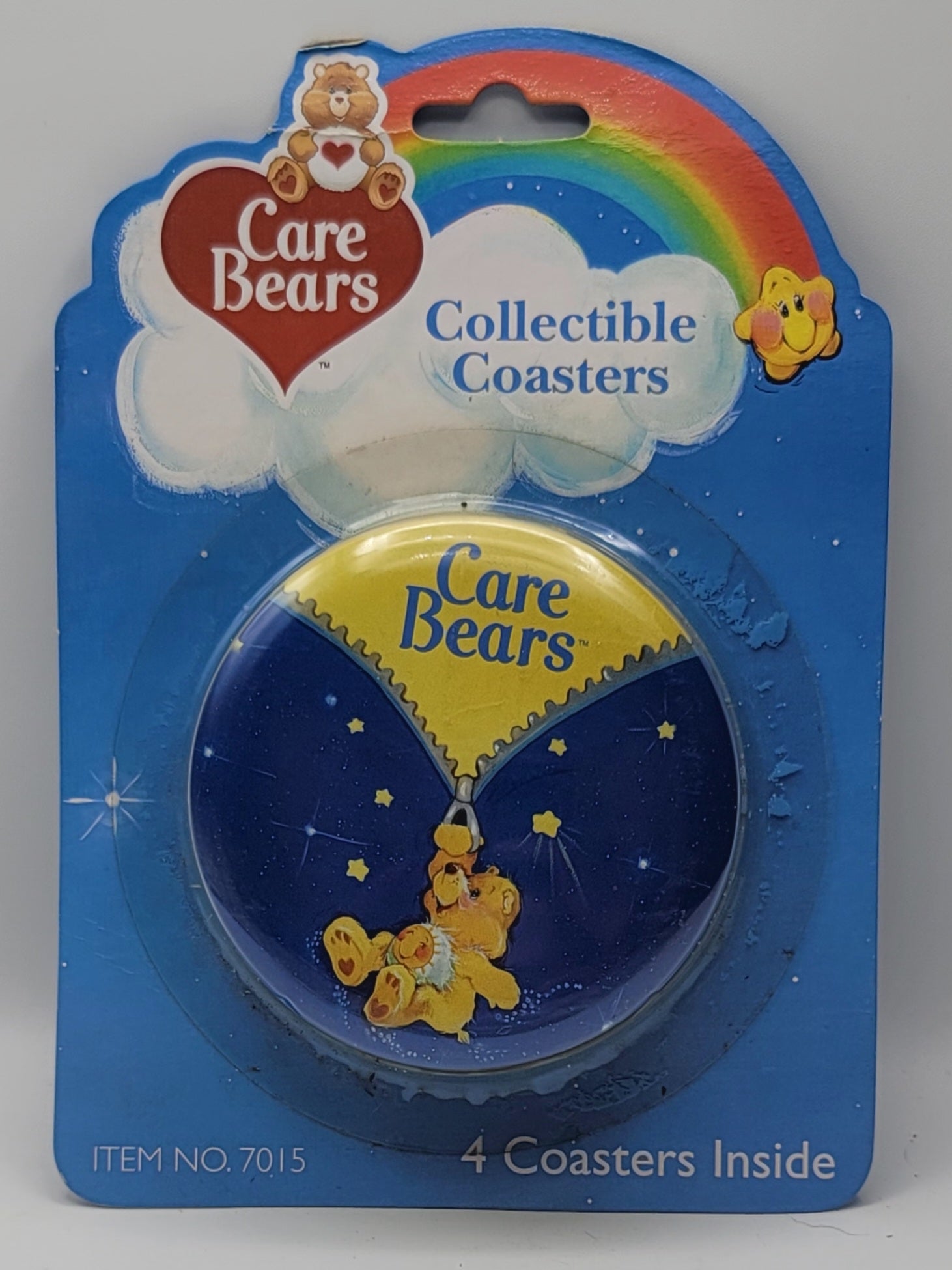 A packaged Care Bears collectible coaster set in blue retail blister packaging, showing a round coaster with a yellow bear and starry night design inside a blue cloud, plus a rainbow and Care Bears logo on the card.
