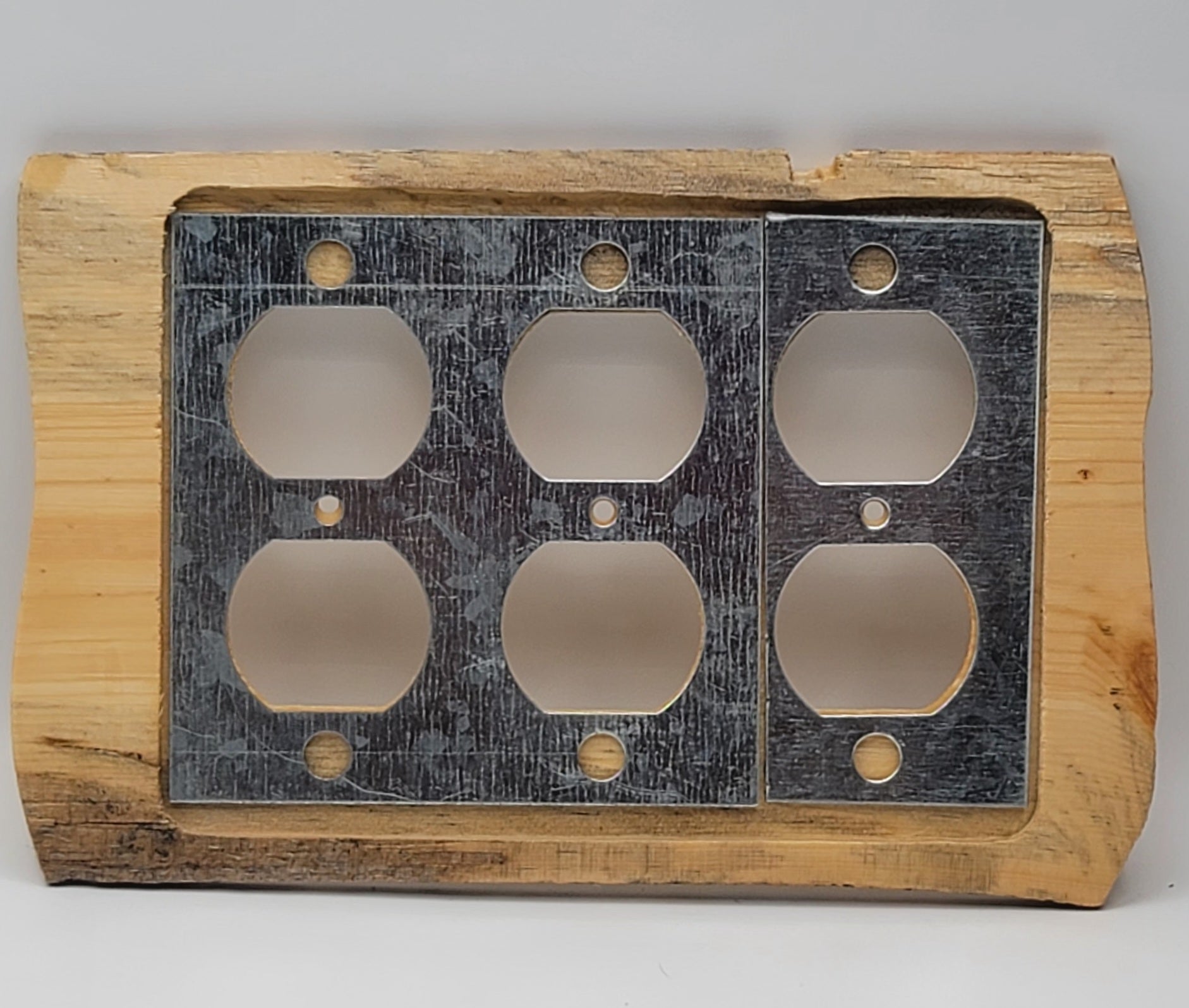 A rustic electrical outlet cover plate featuring a natural wood frame and a dark, weathered metal insert with six cutouts.