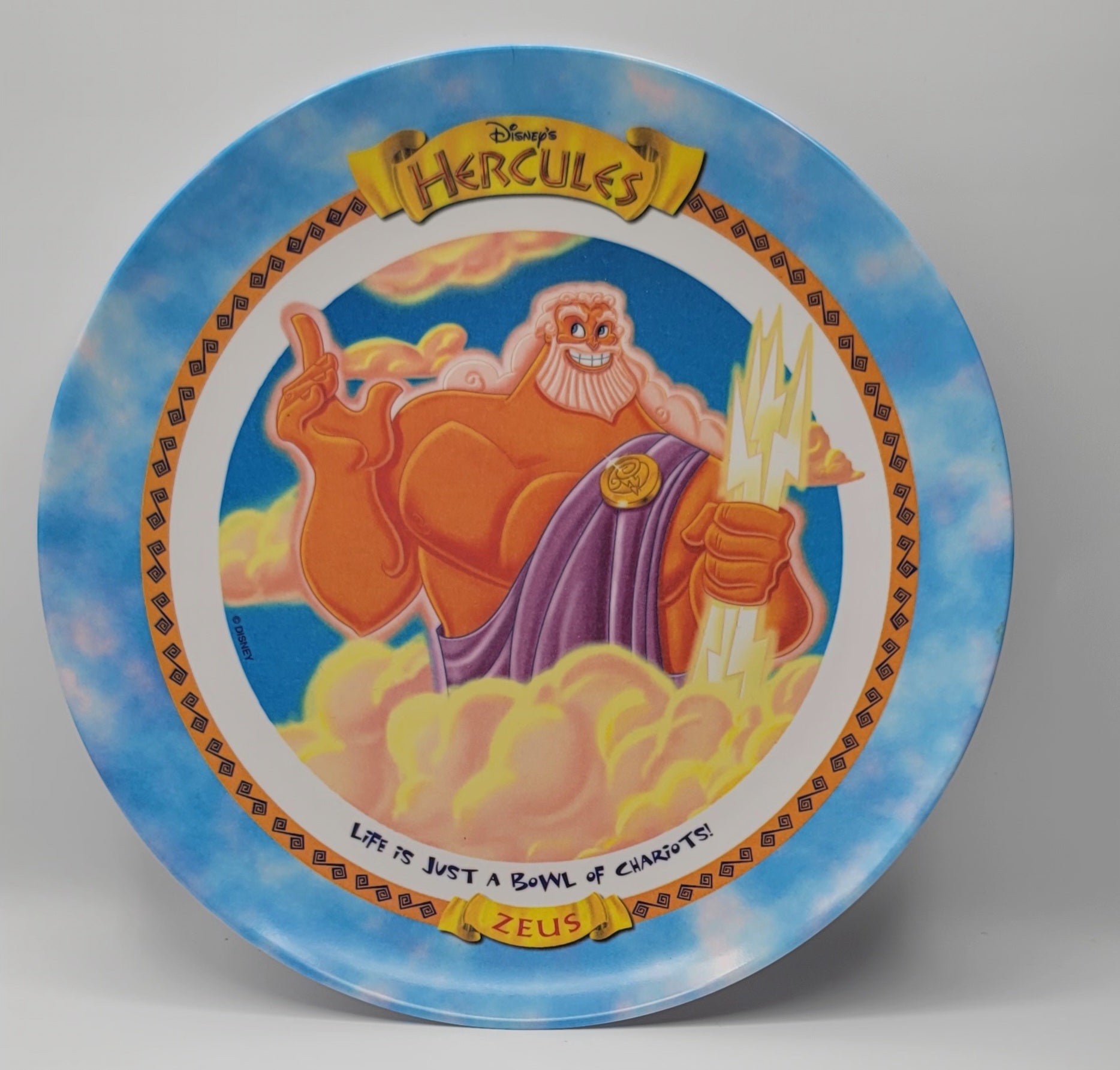 Disney's Hercules Collector's Plate featuring an illustration of Zeus with a gold beard and purple robe, set against a blue sky background with decorative borders.