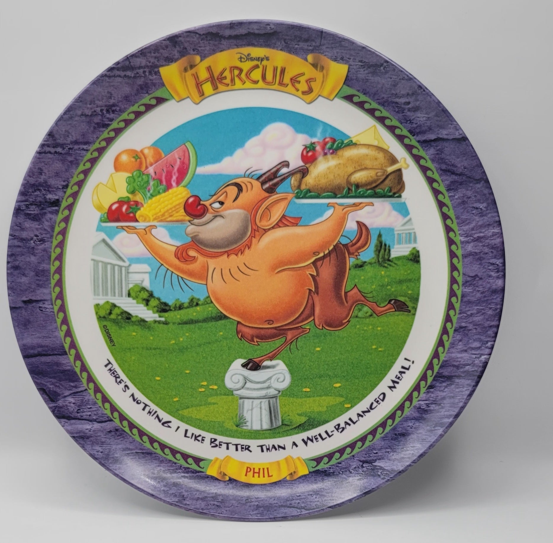 Disney's Hercules collectible decorative plate featuring Phil on a green lawn with a roasted turkey and fruit, surrounded by a purple marbled border and the title 'Hercules' at the top.