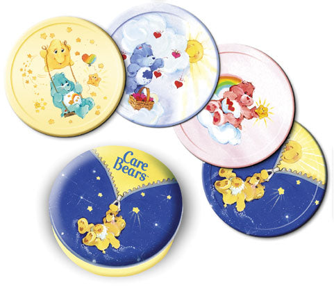 Five round Care Bears themed items arranged on a white background, including a yellow plate with a bear and heart motif, a blue plate with clouds and a bear, a pink plate with a bear and rainbow, a blue night-sky plate with stars, and a yellow-and-blue Care Bears logo plate.