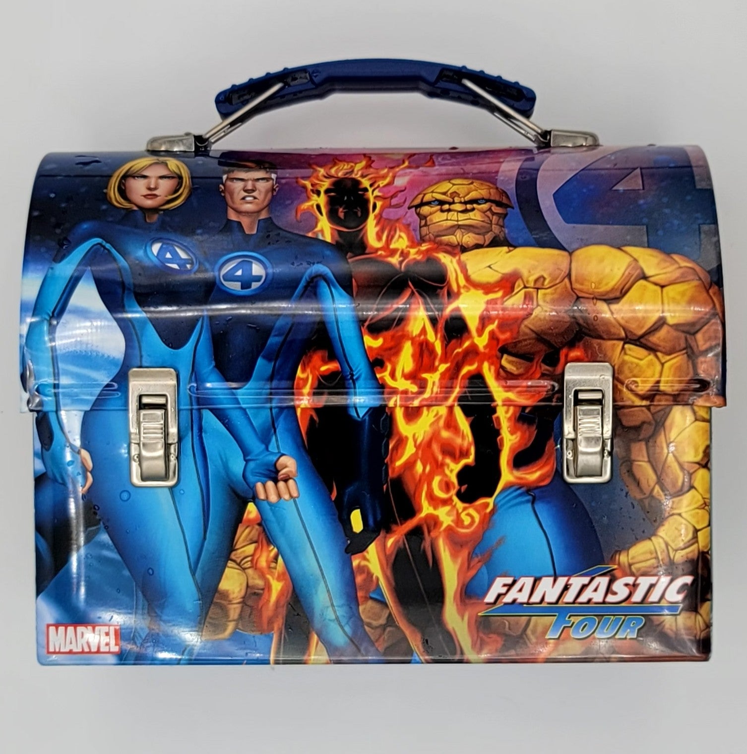 A Marvel Fantastic Four metal lunch box featuring printed artwork of the characters with blue, orange, and black tones, a top handle, and silver latch closures.