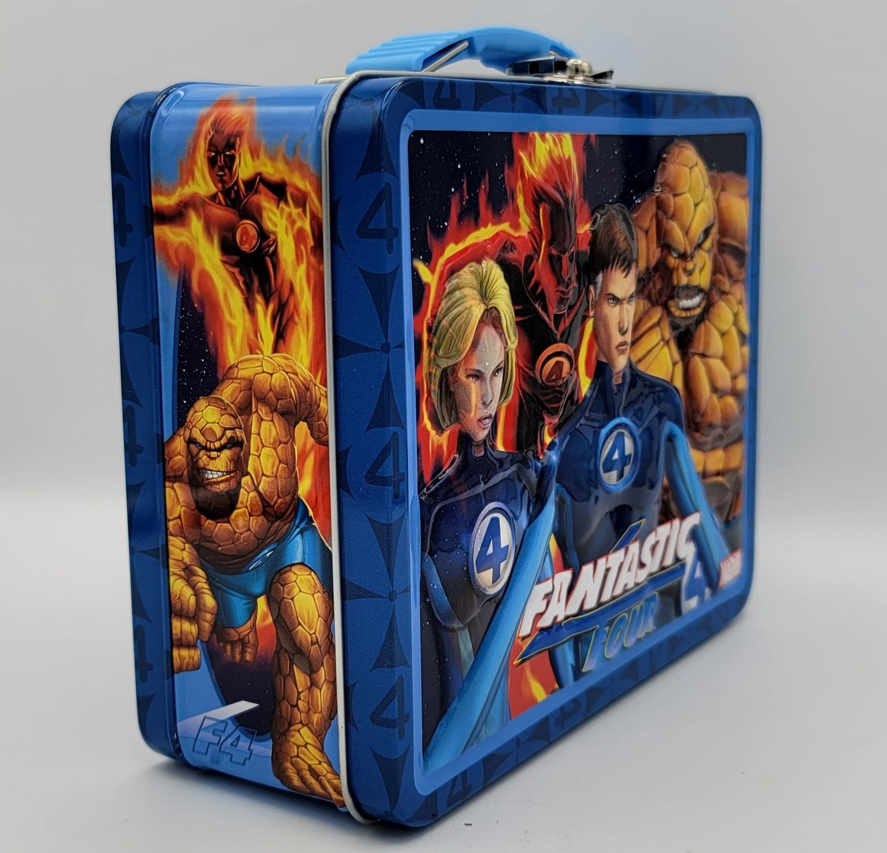 A blue metal lunch box featuring printed artwork of the Fantastic Four characters, including the Human Torch, Invisible Woman, Invisible Man, and The Thing, with the 'Fantastic Four' logo on the front.