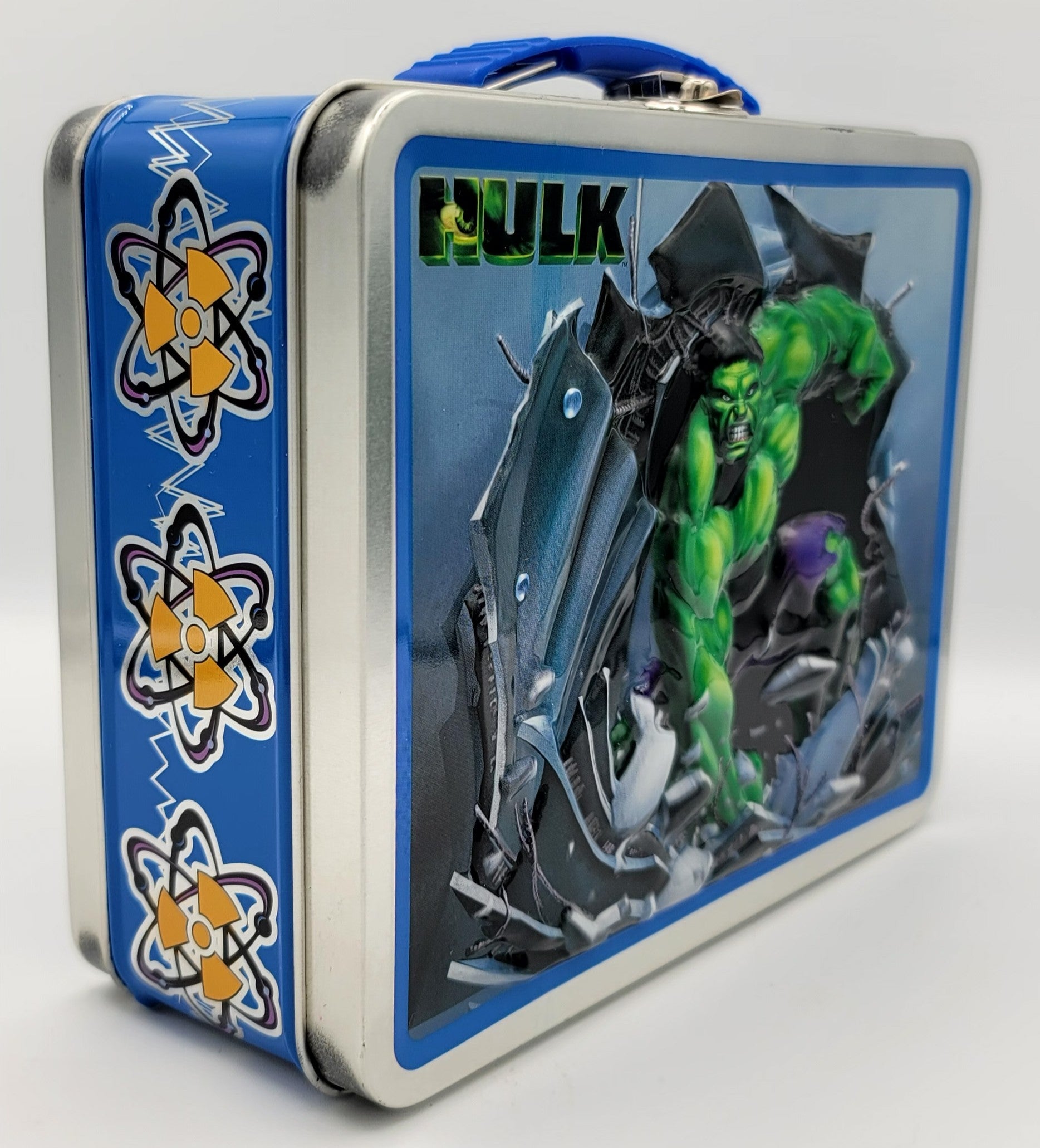 A rectangular metal lunch box with a blue handle, featuring Marvel's Hulk on the front panel and atom symbols on the blue side panel.